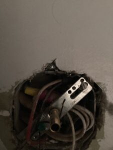 Electricians troubleshooting and repairing wiring for a bathroom light fixture